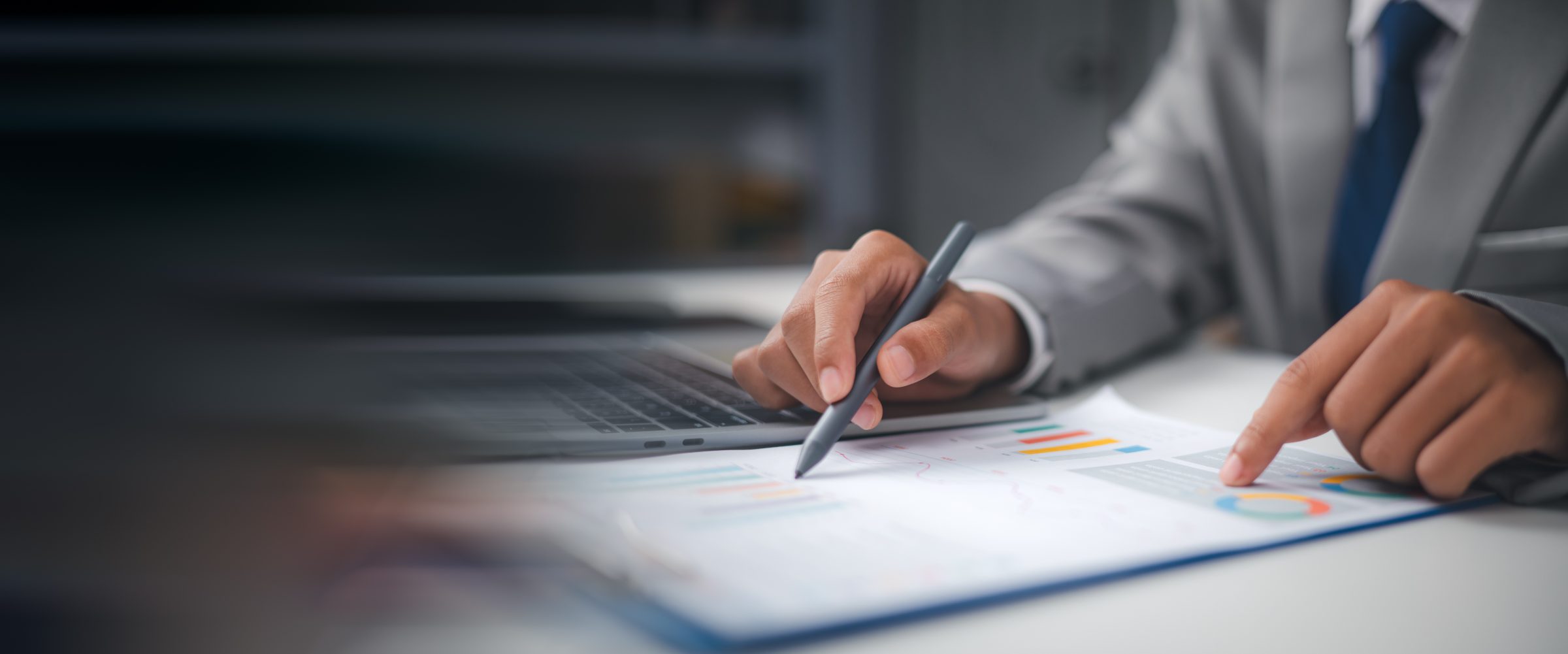 Business professional in gray suit analyzing colorful bar chart with stylus pen